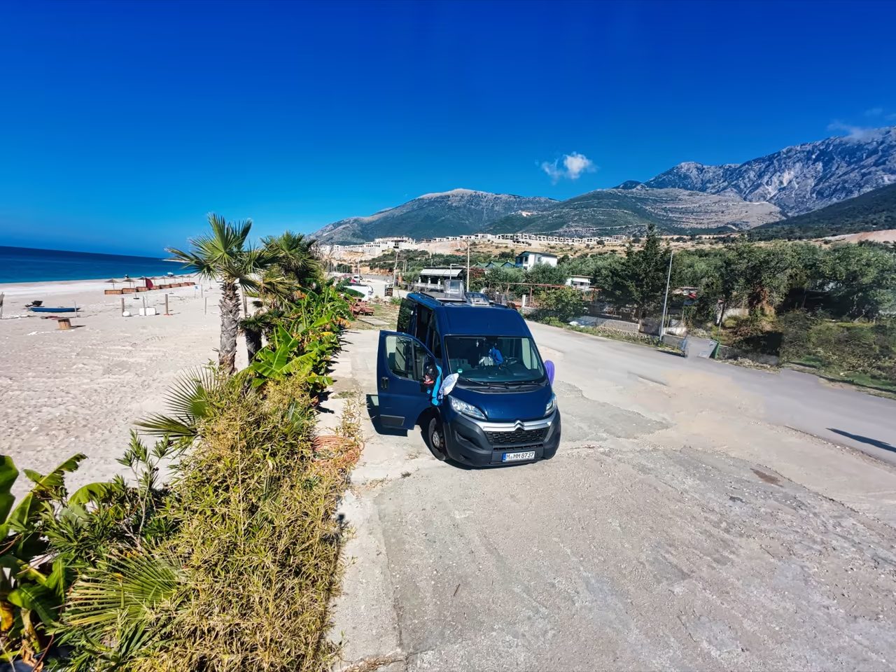 Albanien im Camper: Unsere Route & Geheimtipps für Vanlife 7 Campervan am Strand mit Bergen im Hintergrund