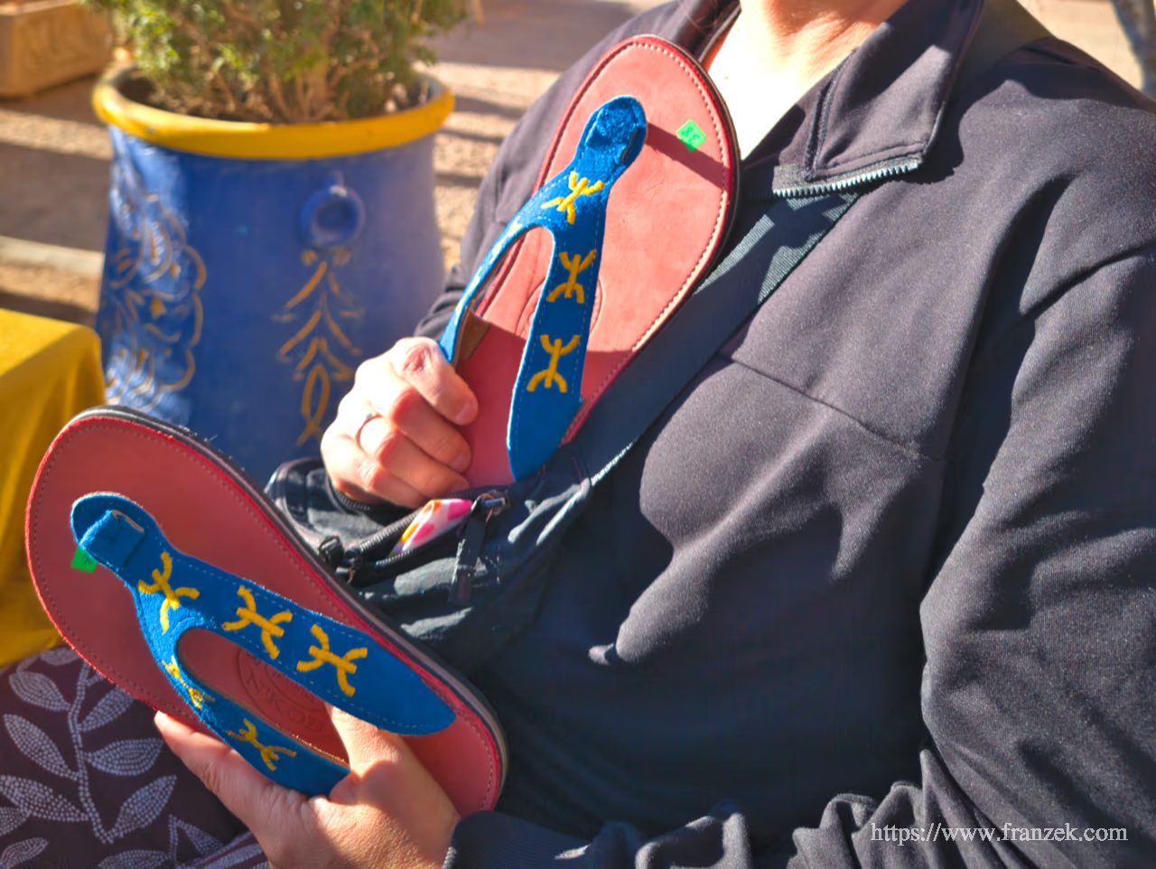 Süd-Marokko Mietwagen-Route: Kosten & Tipps (Anti-Atlas) 54 Nahaufnahme von traditionellen Berber-Sandalen aus blauem Leder mit bunten Stickereien, die in der Hand gehalten werden.