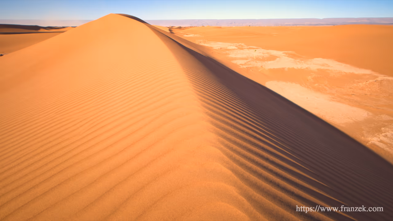 Süd-Marokko Mietwagen-Route: Kosten & Tipps (Anti-Atlas) 48 Nahaufnahme einer hohen Sanddüne im Erg Chegaga. Eine scharfe Kamm-Linie trennt Licht- und Schattenseite. Der Sand zeigt gleichmäßige, feine Windrippeln unter einem klaren Himmel.