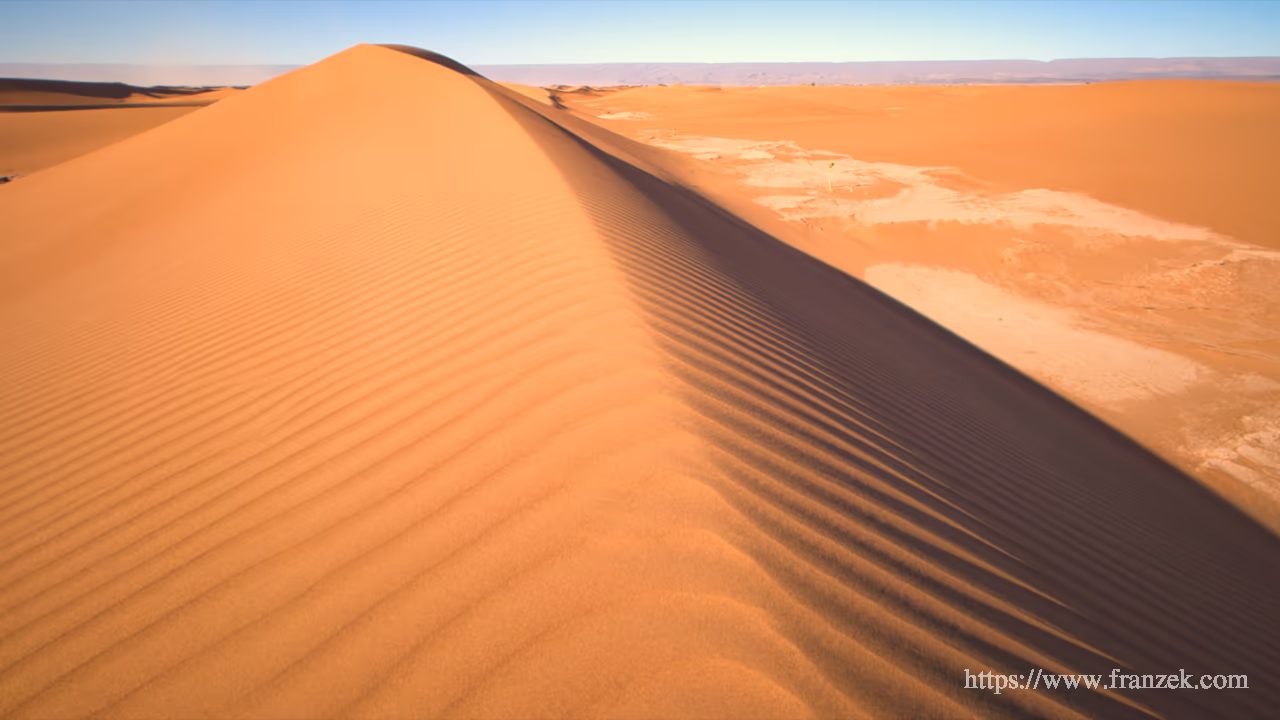 Süd-Marokko Mietwagen-Route: Kosten & Tipps (Anti-Atlas) 48 Nahaufnahme einer hohen Sanddüne im Erg Chegaga. Eine scharfe Kamm-Linie trennt Licht- und Schattenseite. Der Sand zeigt gleichmäßige, feine Windrippeln unter einem klaren Himmel.