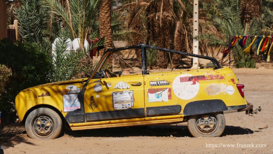 Wohnmobil Werkstatt Marokko: 4 Hotspots, Kosten & Ersatzteile (2026) 1 Ein gelb-weißer Renault 4 (R4) parkt vor Palmen in einer Wüstenumgebung in Marokko.